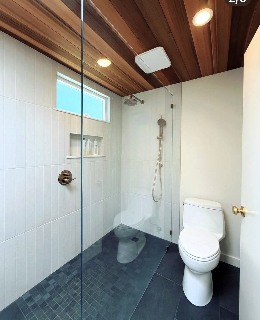 Bathroom shower after remodel — walk-in glass shower with white tile