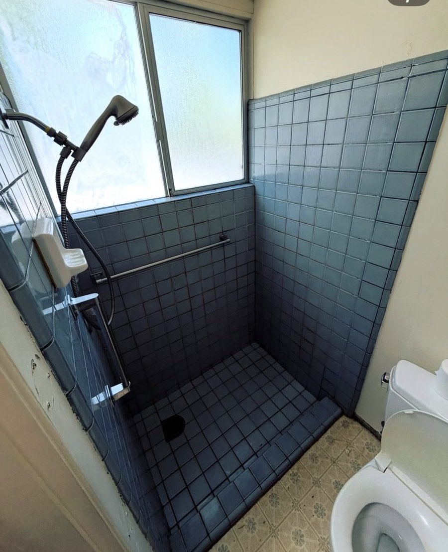 Bathroom shower before remodel — original blue tile stall