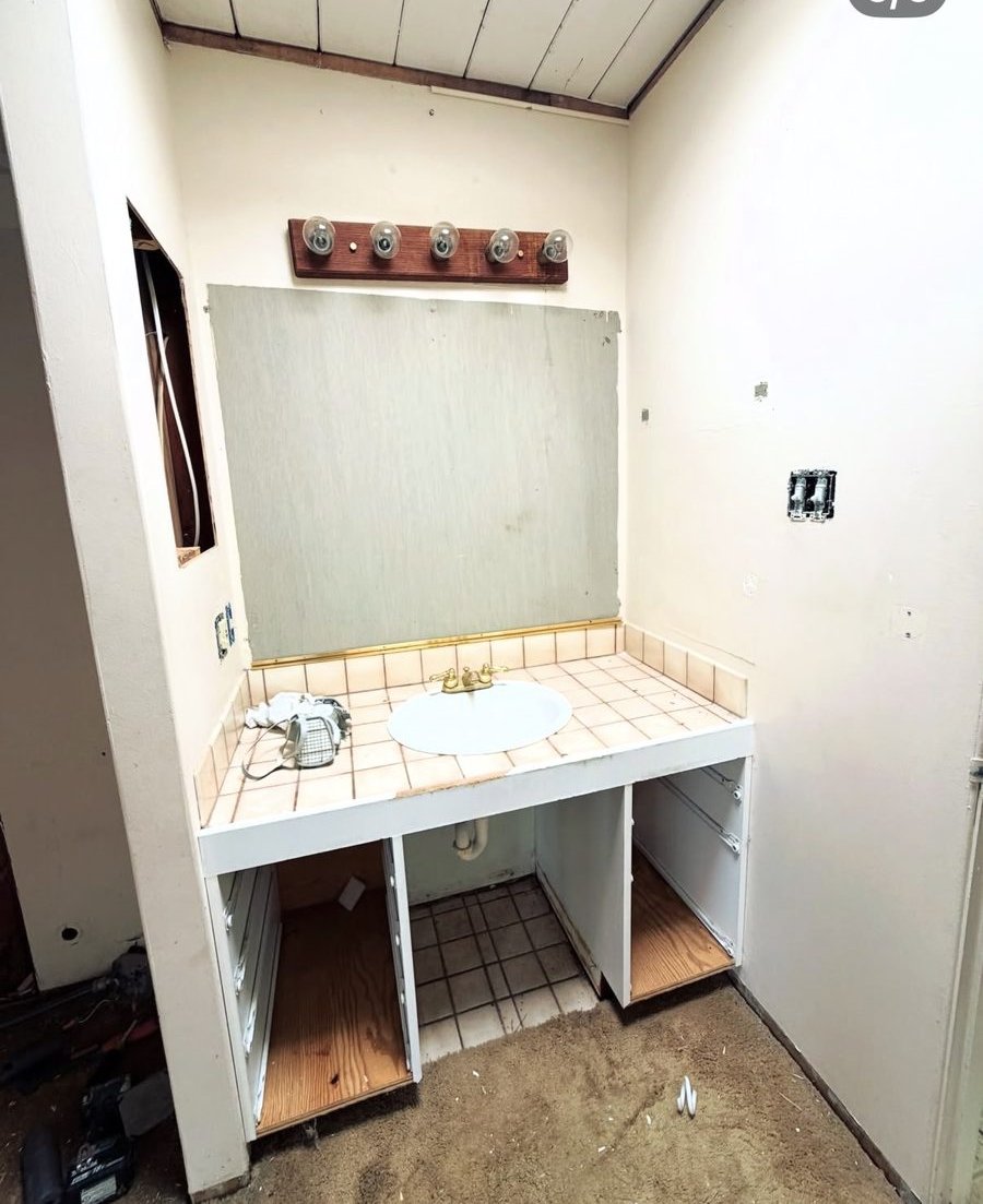 Bathroom vanity before remodel — original tile counter and cabinetry