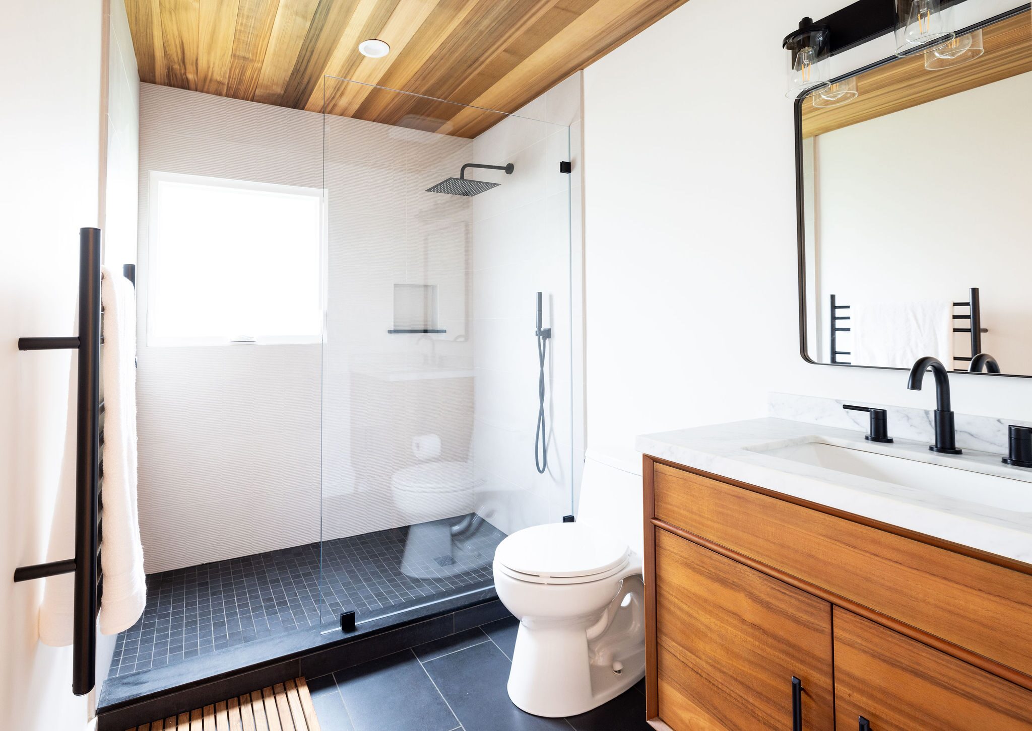 Full bathroom remodel with walk-in glass shower, cedar ceiling and mid-century vanity by Build Shepherd